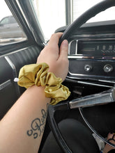 Load image into Gallery viewer, golden silky scrunchie on wrist holding on to a vintage steering wheel